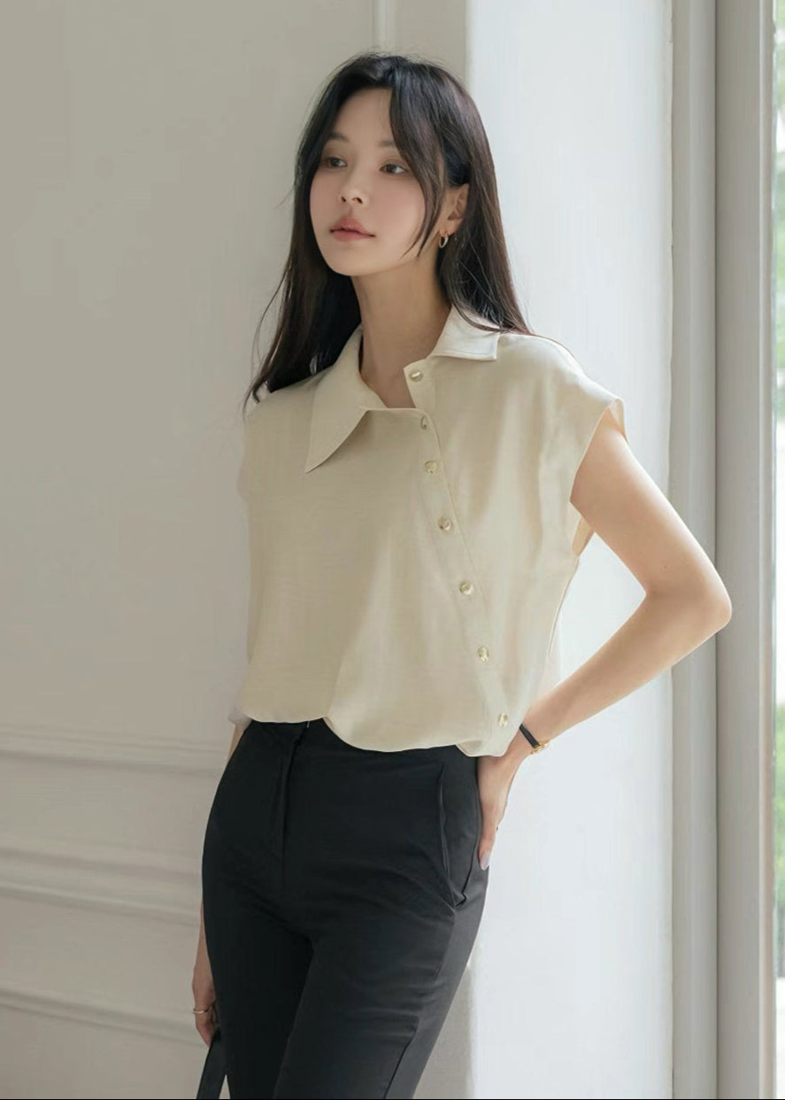 Woman wearing a beige sleeveless blouse and black pants in a neutral setting